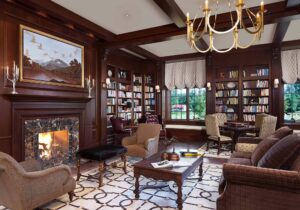 The wood paneled guest library with fireplace and equestrian rug at the luxury Salamander Resort & Spa in Middleburg, Va