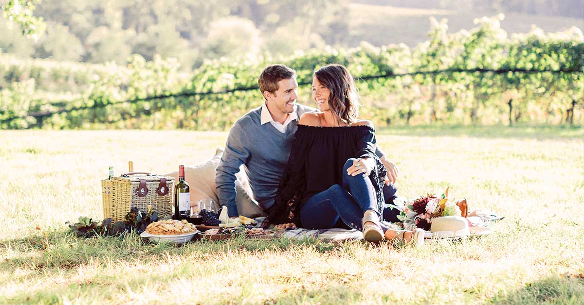 A young couple on a romantic fall wine picnic at Barboursville Winery with a well-packed picnic basket.