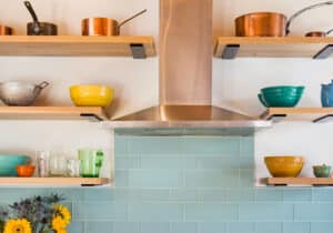 Photo of modern kitchen showing stove vent and colorful bowls on shelves