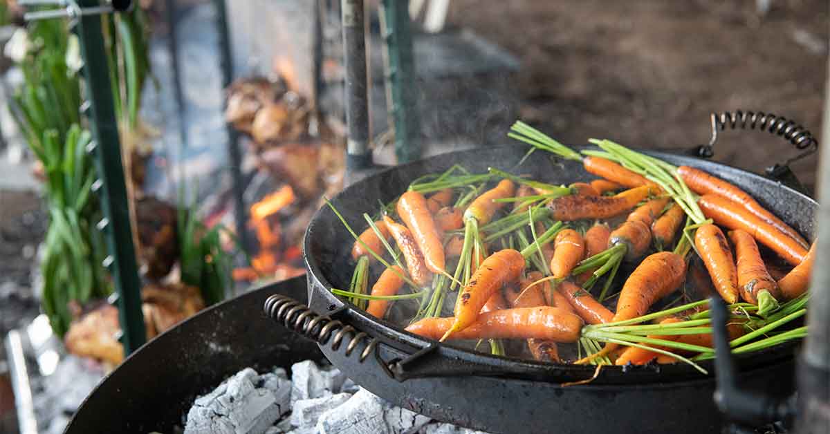 Young carrots being roasted in a cast iron skillet over an open fire at a special wine dinner at Veritas Winery in Virginia.