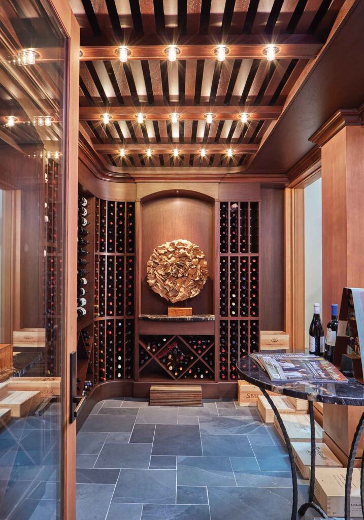 Custom wine cellar designed by Purple Cherry Architects with rich wood walls, wood ceiling and slate floor. Dramatic lighting and art.