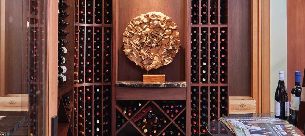 Custom wine cellar with rich wood walls, wood ceiling and slate floor. Dramatic lighting and art with glass doors.