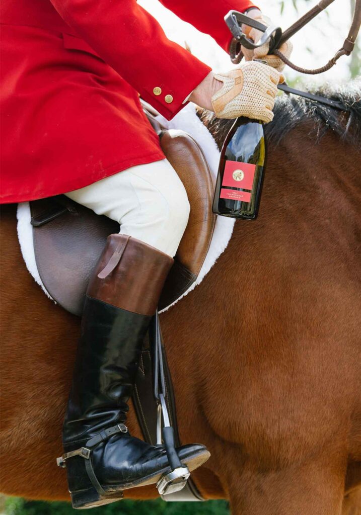 A bottle of Southwest Mountains Petite Verdot Reserve carried by horse rider on english saddle.