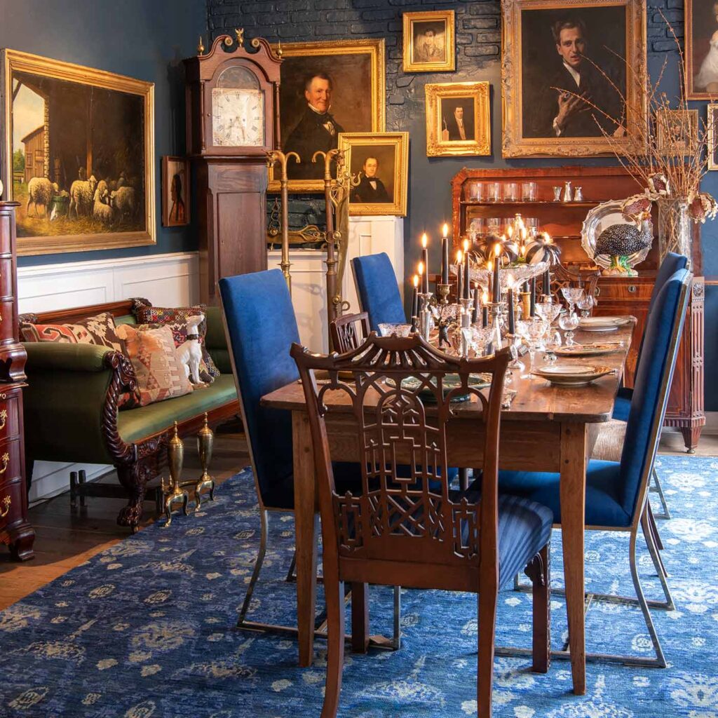 Photo of the interior at Antiques on Washington Street, showcasing dining table, chairs, couch, grandfather clock and paintings