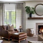Photo of warm white living room with fireplace, bookshelves and leather armchair designed by Casey Sanford of Richmond Virginia