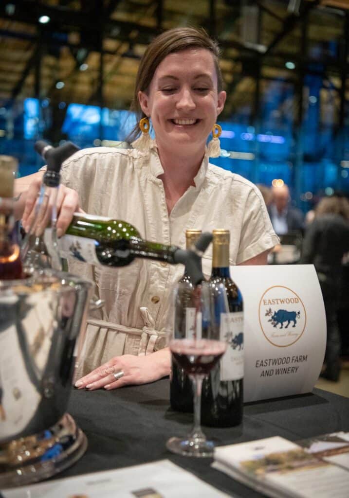 Photo of woman from Eastwood Farm and Winery pouring wine into a glass