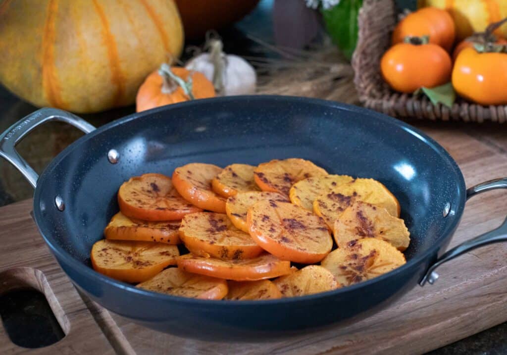 fuyu persimmons sliced and roasting in a pan