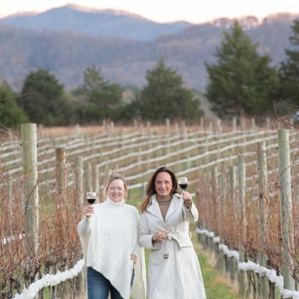 Robin Bethke and Jenny Stoltz in winter vineyards with wine glasses