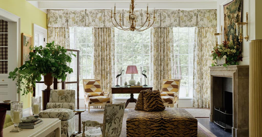 Chartreuse living room in the 2025 Southern Living Idea House by Charlotte Moss, focusing on large picture windows with floral Schumacher draperies and views of the surrounding Virginia landscape.