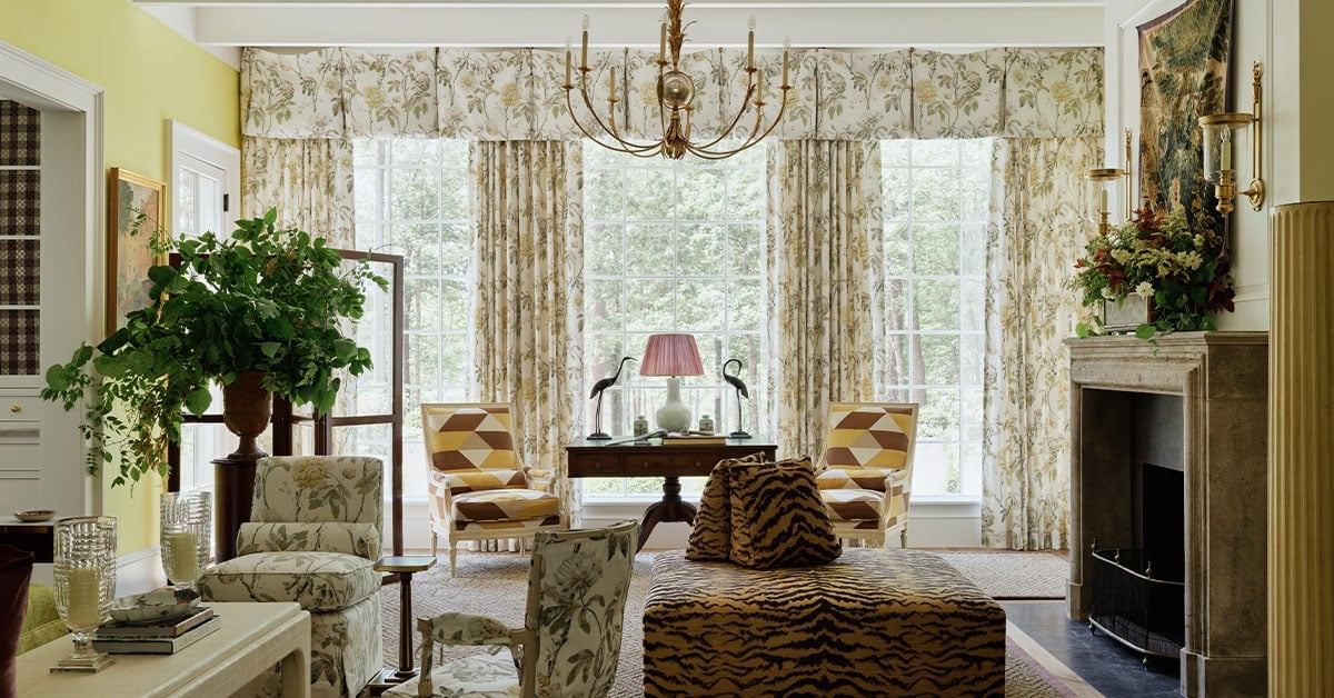 Chartreuse living room in the 2025 Southern Living Idea House by Charlotte Moss, focusing on large picture windows with floral Schumacher draperies and views of the surrounding Virginia landscape.