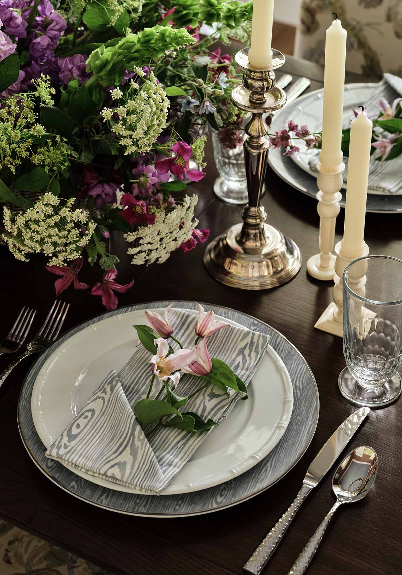 Close-up of dining room table setting in the 2025 Southern Living Idea House by Charlotte Moss, featuring elegant china, crystal glassware, and floral centerpiece.
