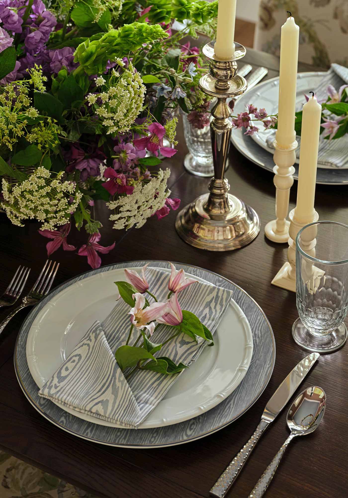 Close-up of dining room table setting in the 2025 Southern Living Idea House by Charlotte Moss, featuring elegant china, crystal glassware, and floral centerpiece.
