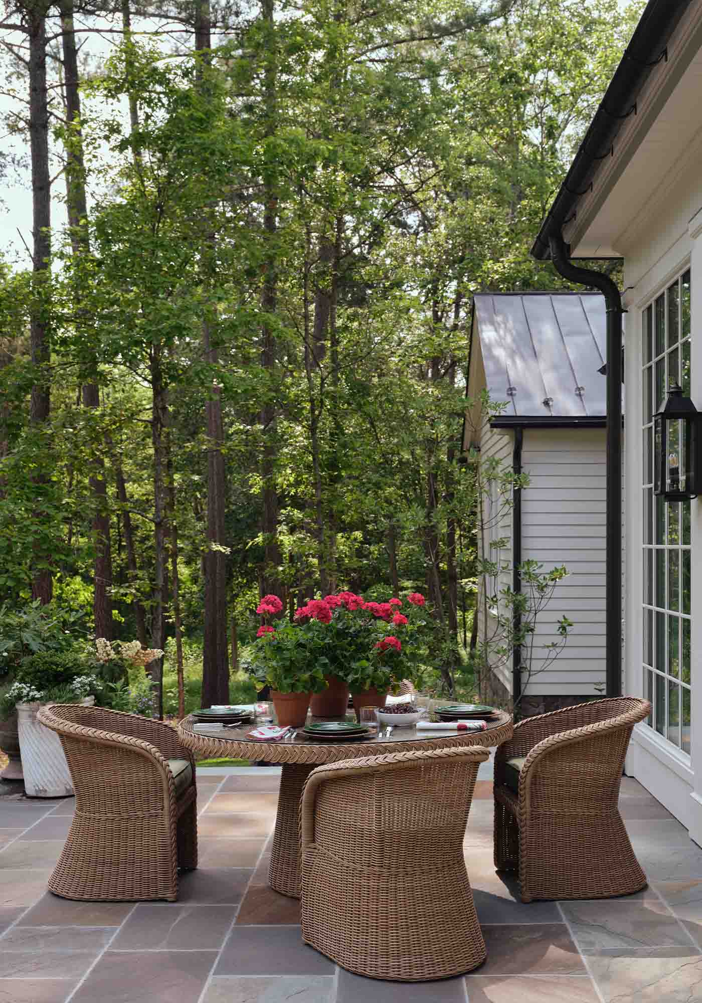 Patio set at the 2025 Southern Living Idea House by Charlotte Moss, featuring cushioned seating, a central coffee table, and views of the landscaped garden.