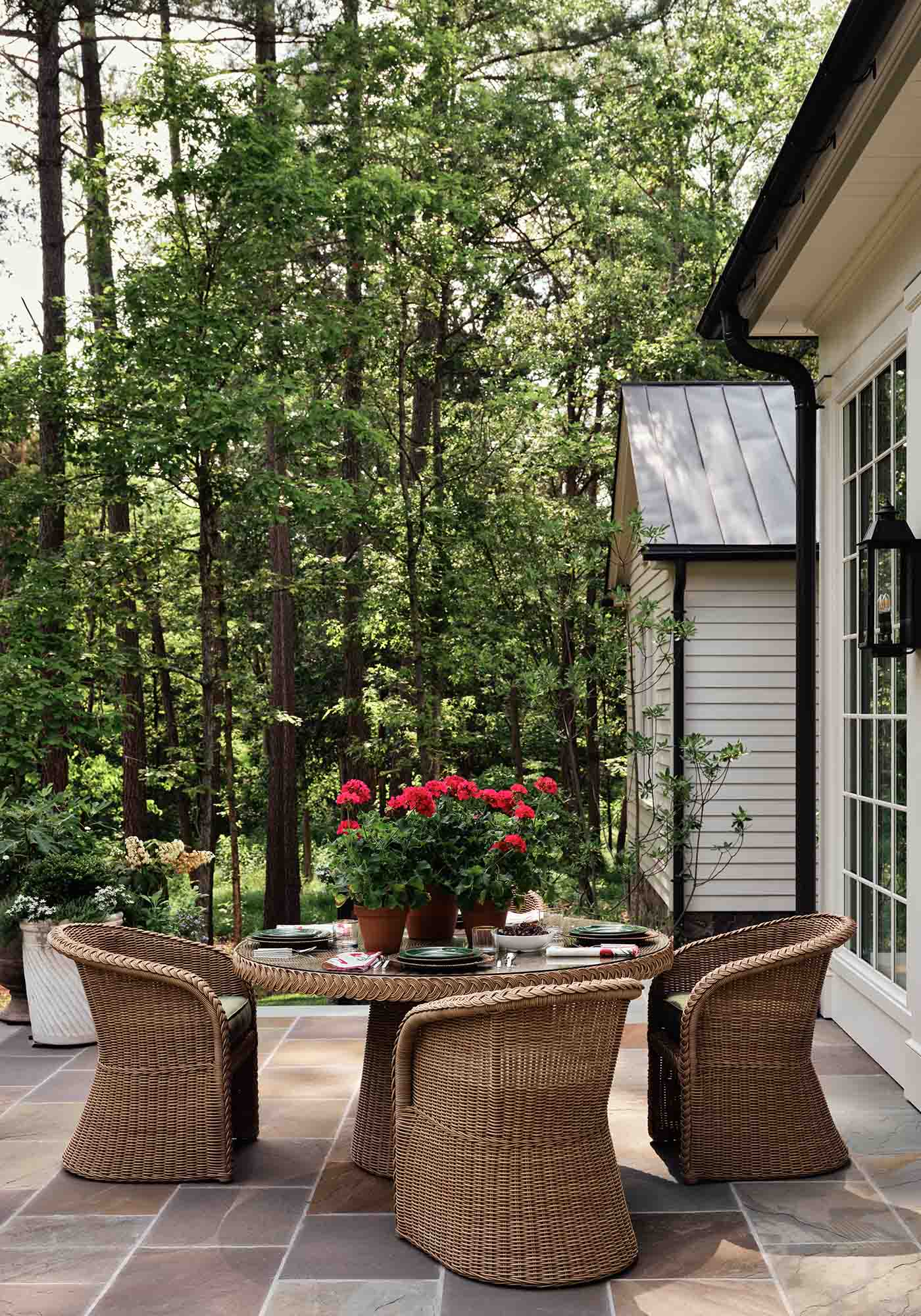 Patio set at the 2025 Southern Living Idea House by Charlotte Moss, featuring cushioned seating, a central coffee table, and views of the landscaped garden.