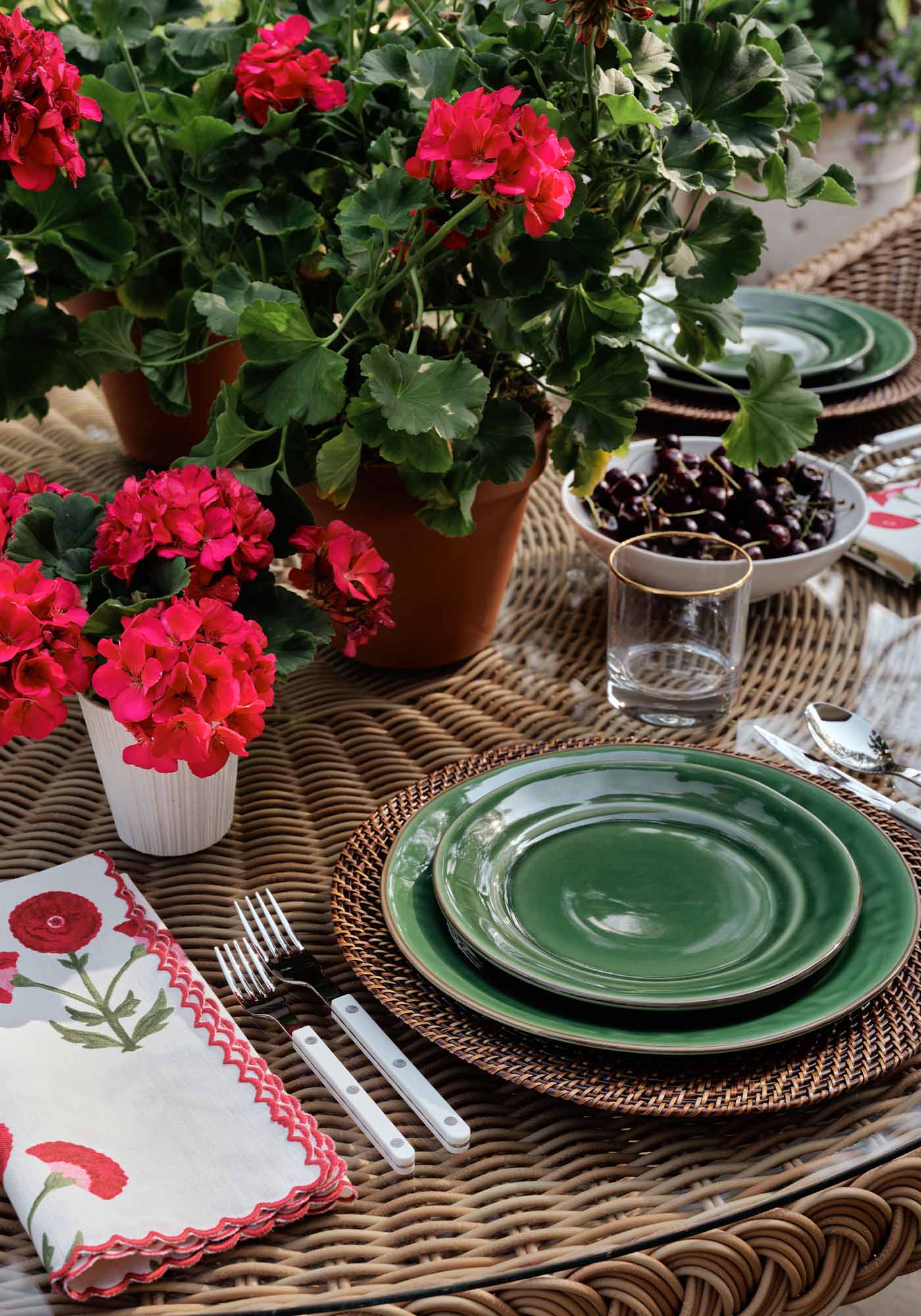 Close-up of the patio set tablescape at the 2025 Southern Living Idea House by Charlotte Moss, featuring elegant tableware, glassware, and potted geraniums.