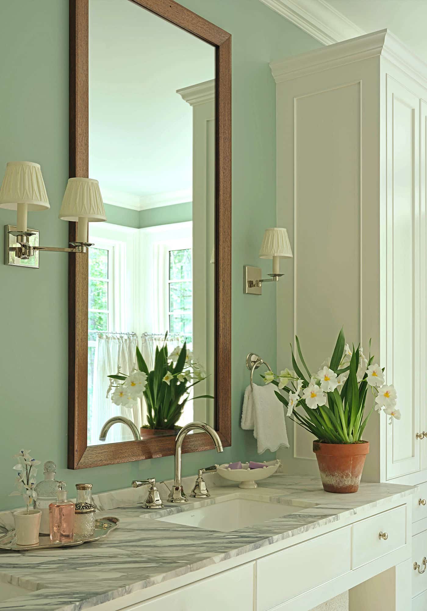 Close-up of the sink and mirror in the master bathroom of the 2025 Southern Living Idea House by Charlotte Moss, showcasing polished fixtures, elegant countertop, and stylish framed mirror.