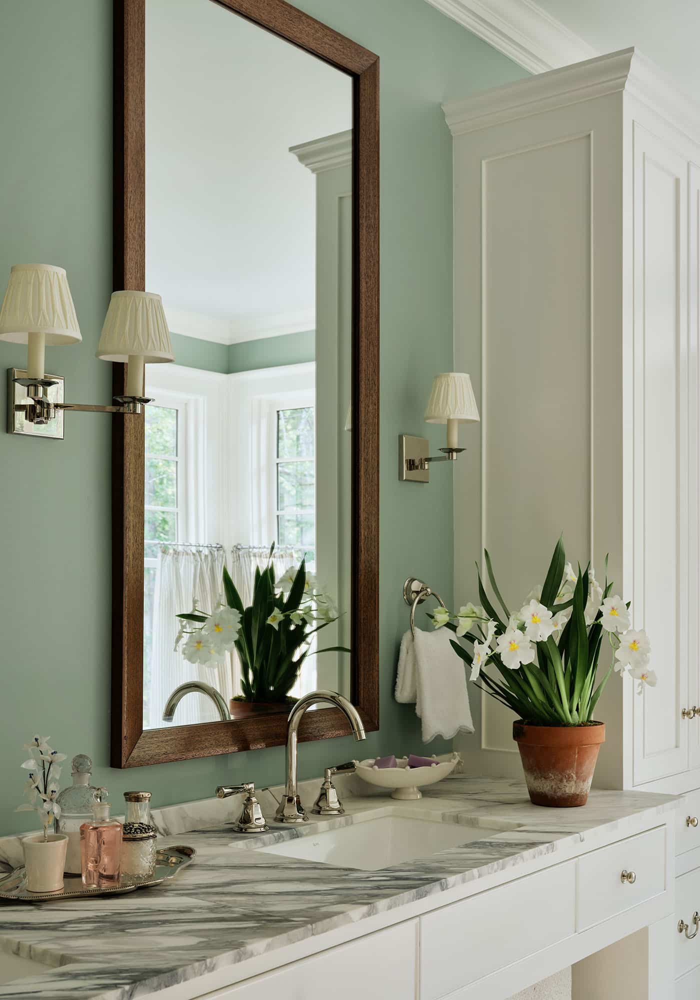 Close-up of the sink and mirror in the master bathroom of the 2025 Southern Living Idea House by Charlotte Moss, showcasing polished fixtures, elegant countertop, and stylish framed mirror.