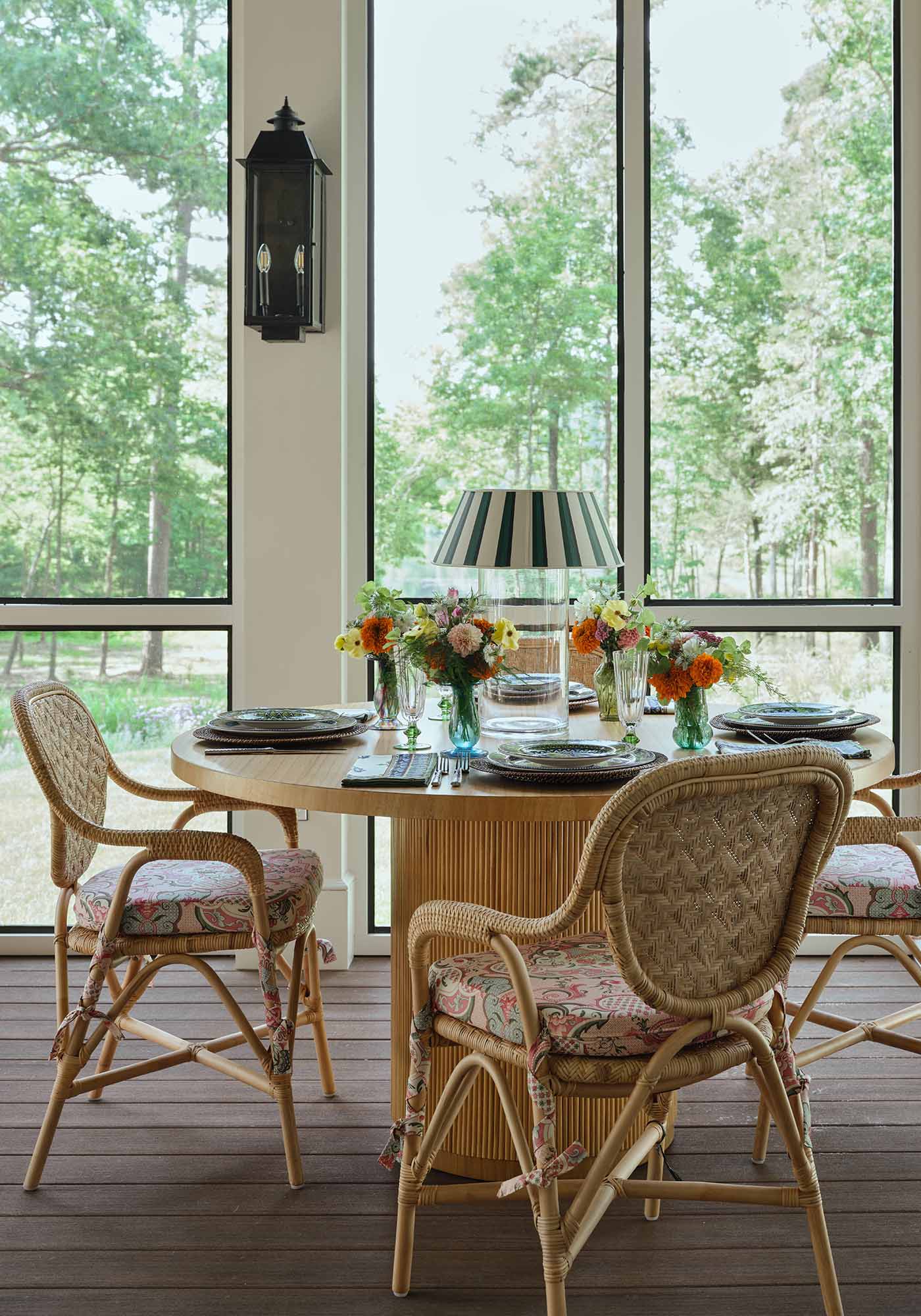 Dining area of the screened porch in the 2025 Southern Living Idea House by Charlotte Moss, with a wooden table set for entertaining and views of the surrounding gardens.