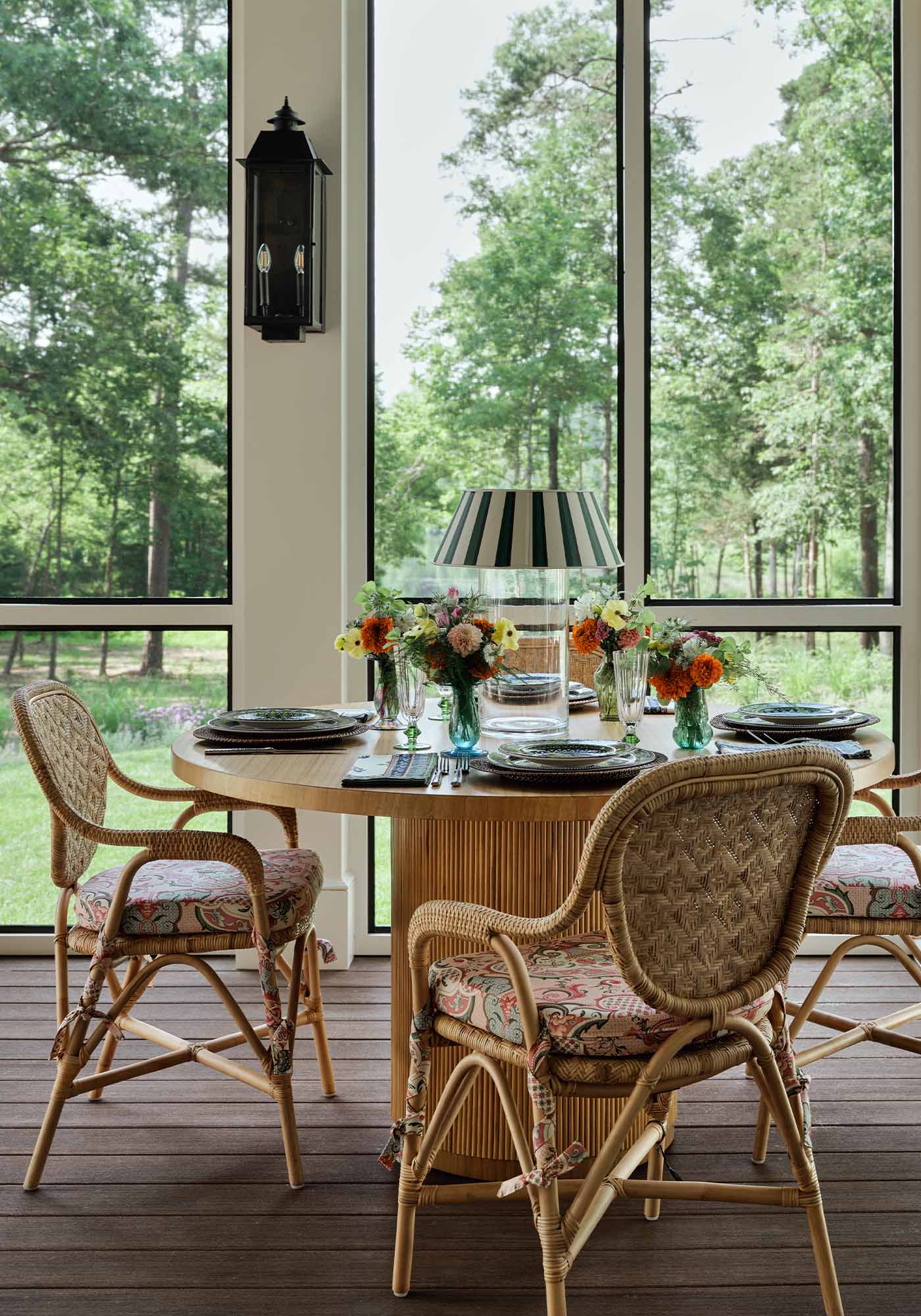 Dining area of the screened porch in the 2025 Southern Living Idea House by Charlotte Moss, with a wooden table set for entertaining and views of the surrounding gardens.