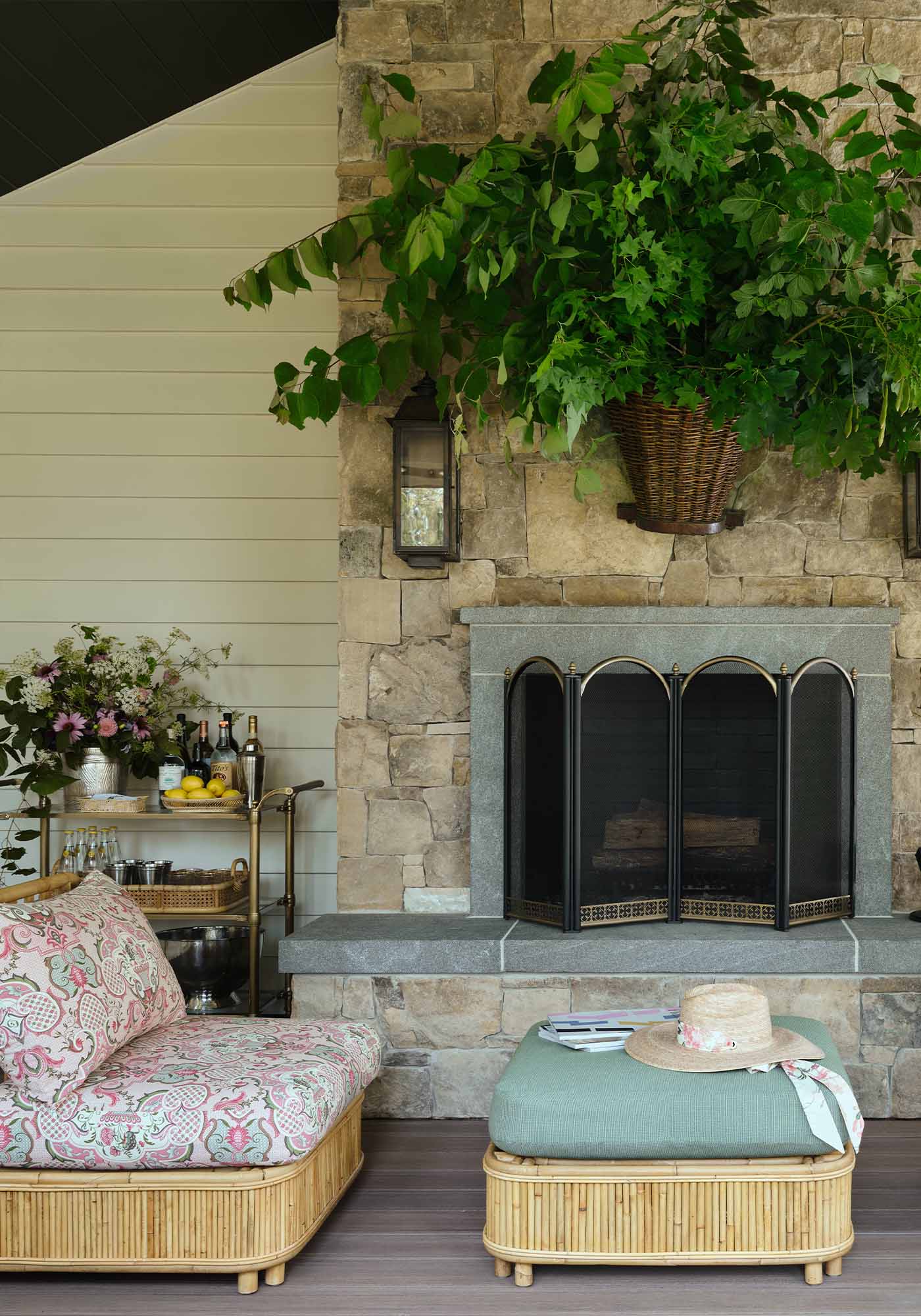 Screened porch in the 2025 Southern Living Idea House by Charlotte Moss, with dining area, slipper chairs by the fireplace, and lounge chairs on TimberTech decking.