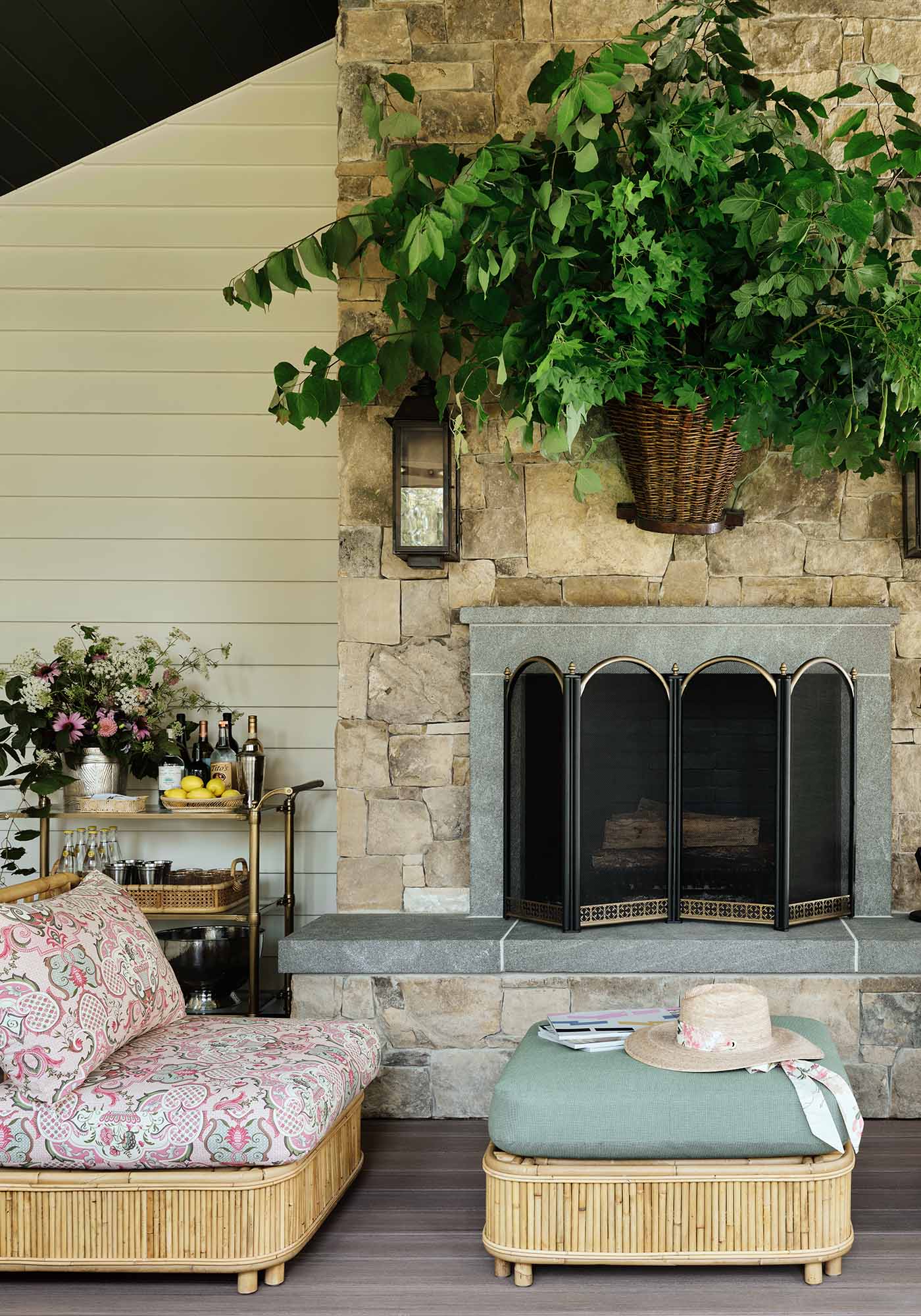 Screened porch in the 2025 Southern Living Idea House by Charlotte Moss, with dining area, slipper chairs by the fireplace, and lounge chairs on TimberTech decking.