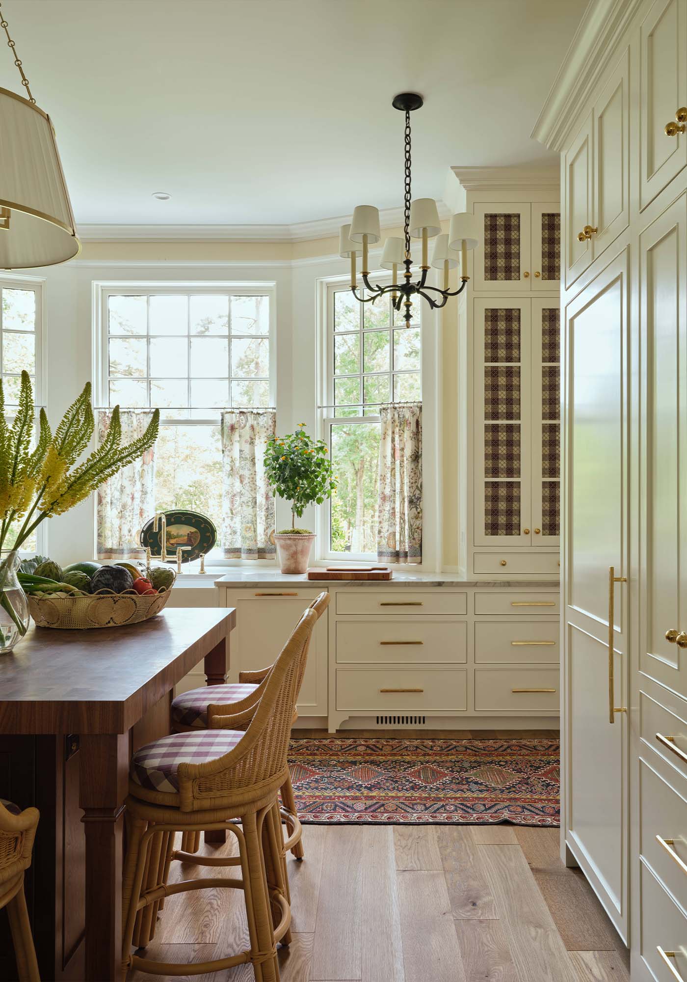 Light-filled kitchen in the 2025 Southern Living Idea House by Charlotte Moss, with creamy cabinetry, butcher-block island, integrated appliances, and decorative plate rails.