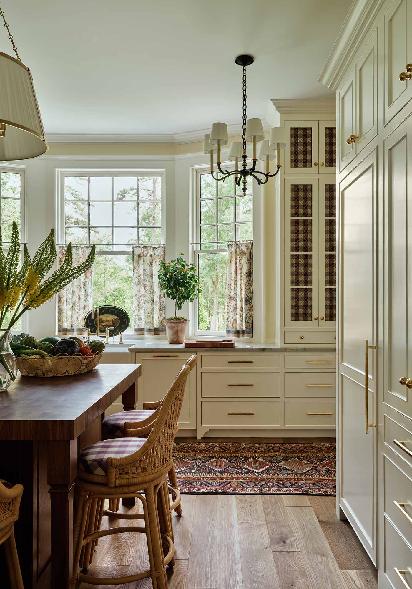 Light-filled kitchen in the 2025 Southern Living Idea House by Charlotte Moss, with creamy cabinetry, butcher-block island, integrated appliances, and decorative plate rails.