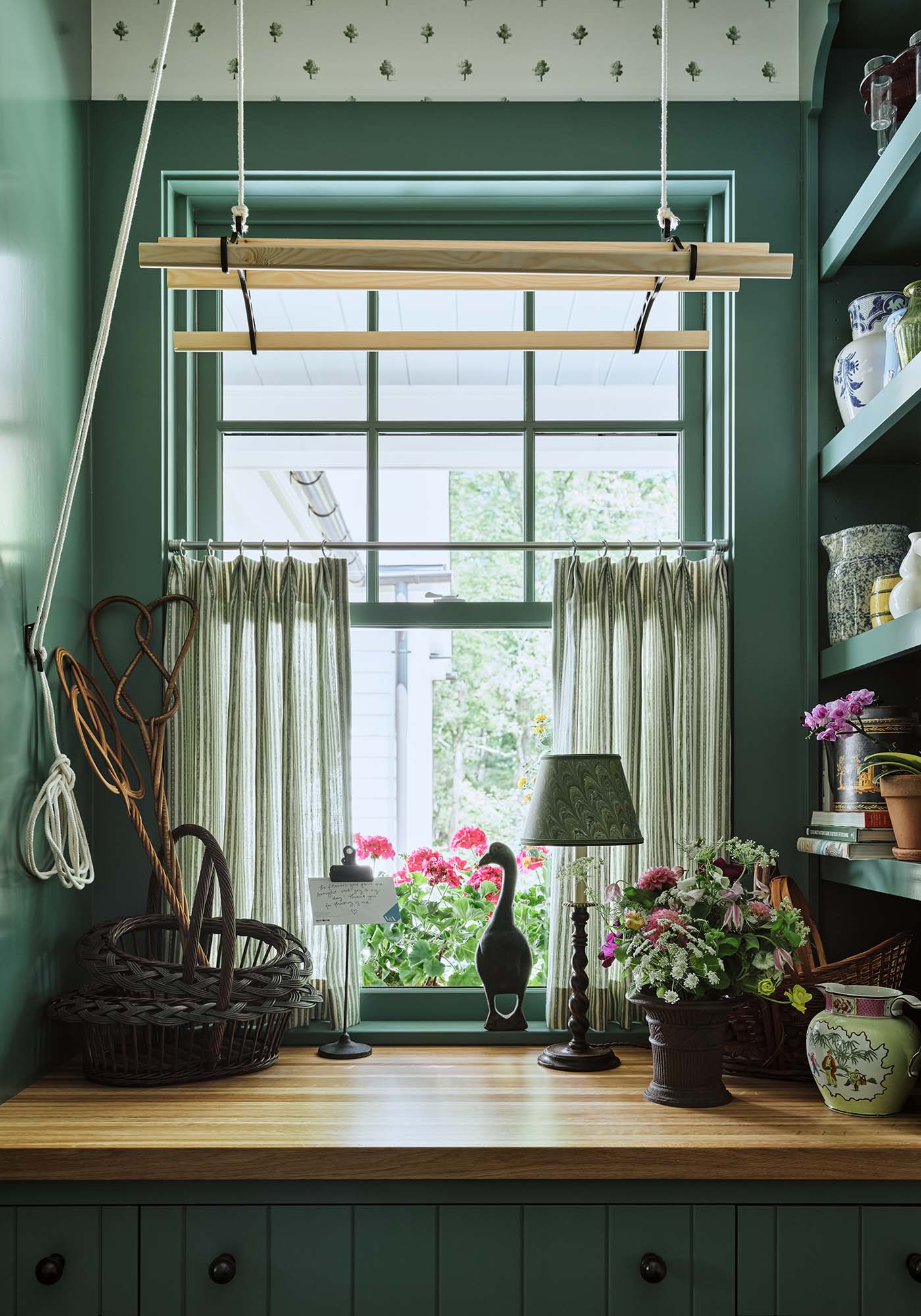 Laundry room window nook in the 2025 Southern Living Idea House by Charlotte Moss, featuring a cozy bench, botanical wallpaper, and natural light streaming through the window.