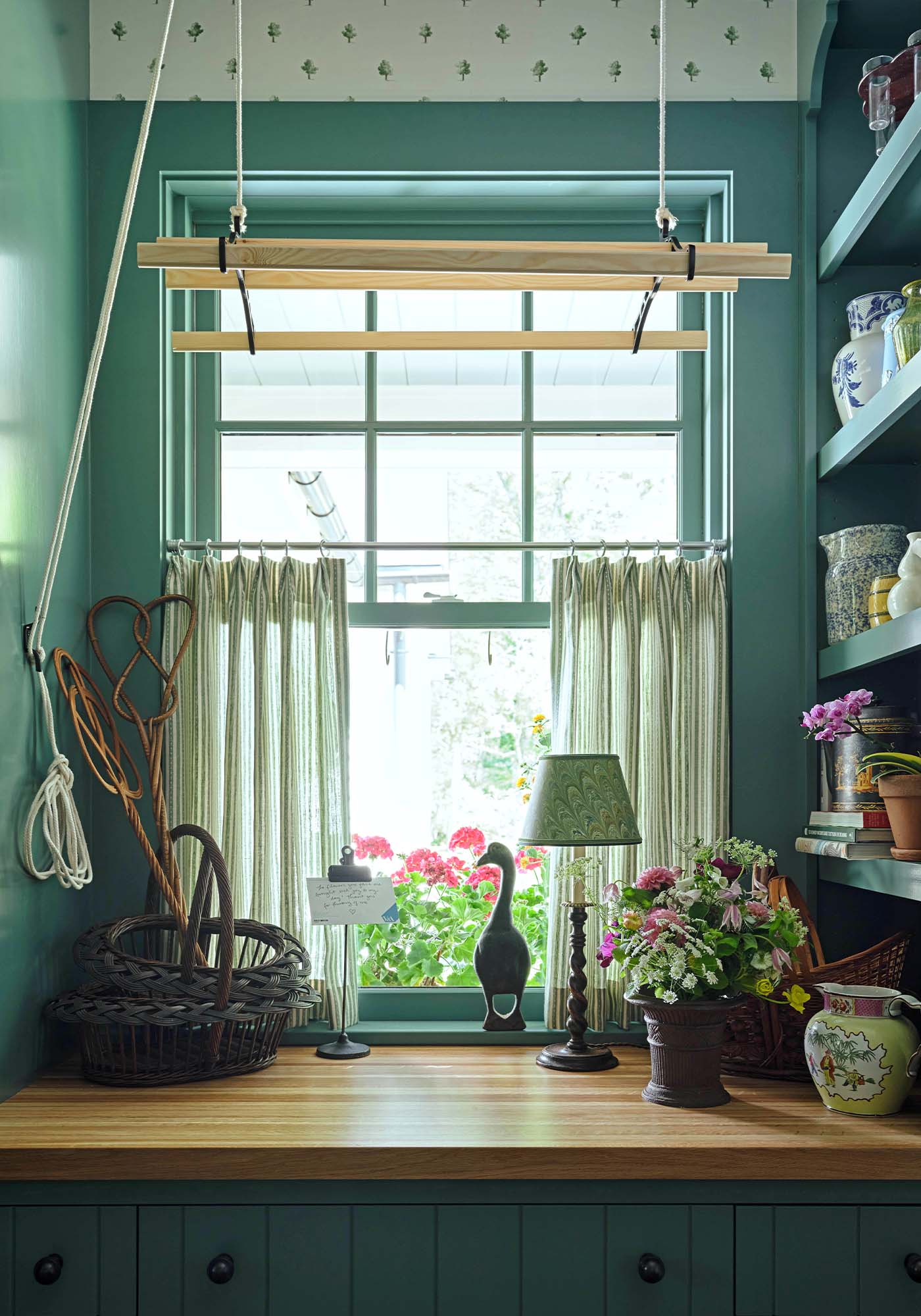 Laundry room window nook in the 2025 Southern Living Idea House by Charlotte Moss, featuring a cozy bench, botanical wallpaper, and natural light streaming through the window.