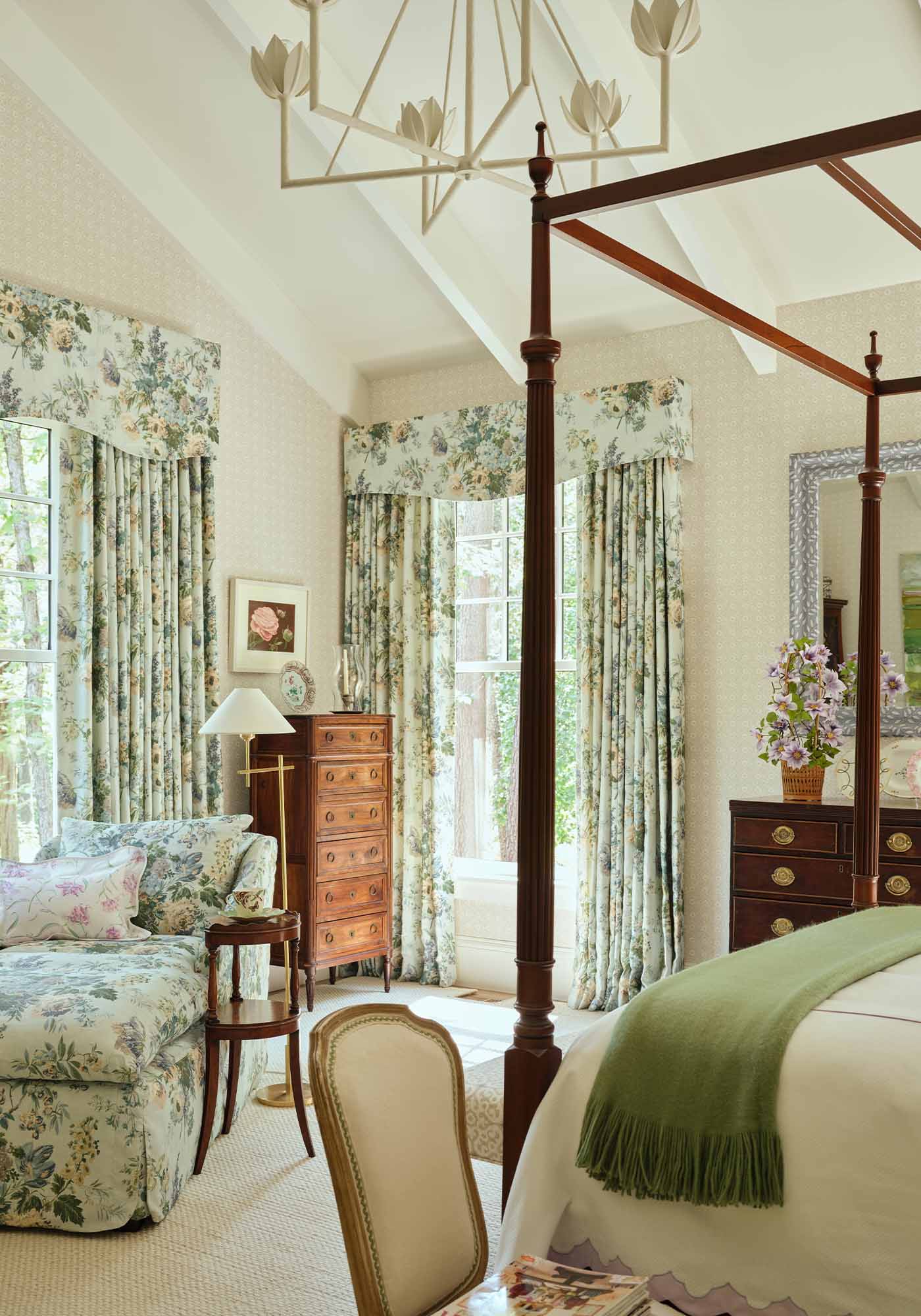 Serene primary bedroom in the 2025 Southern Living Idea House by Charlotte Moss, with four-poster bed in Garden Club floral fabric and antique wooden chests.