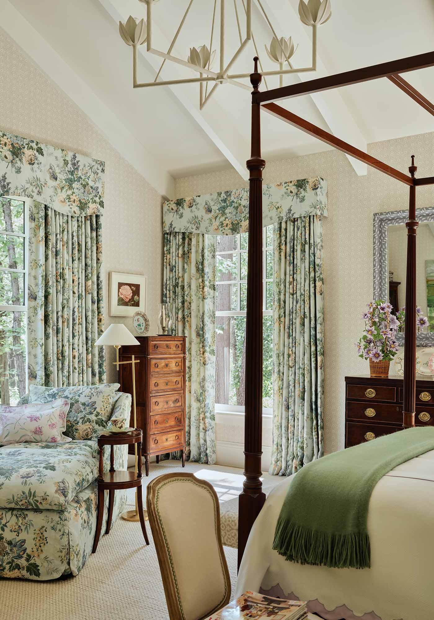 Serene primary bedroom in the 2025 Southern Living Idea House by Charlotte Moss, with four-poster bed in Garden Club floral fabric and antique wooden chests.