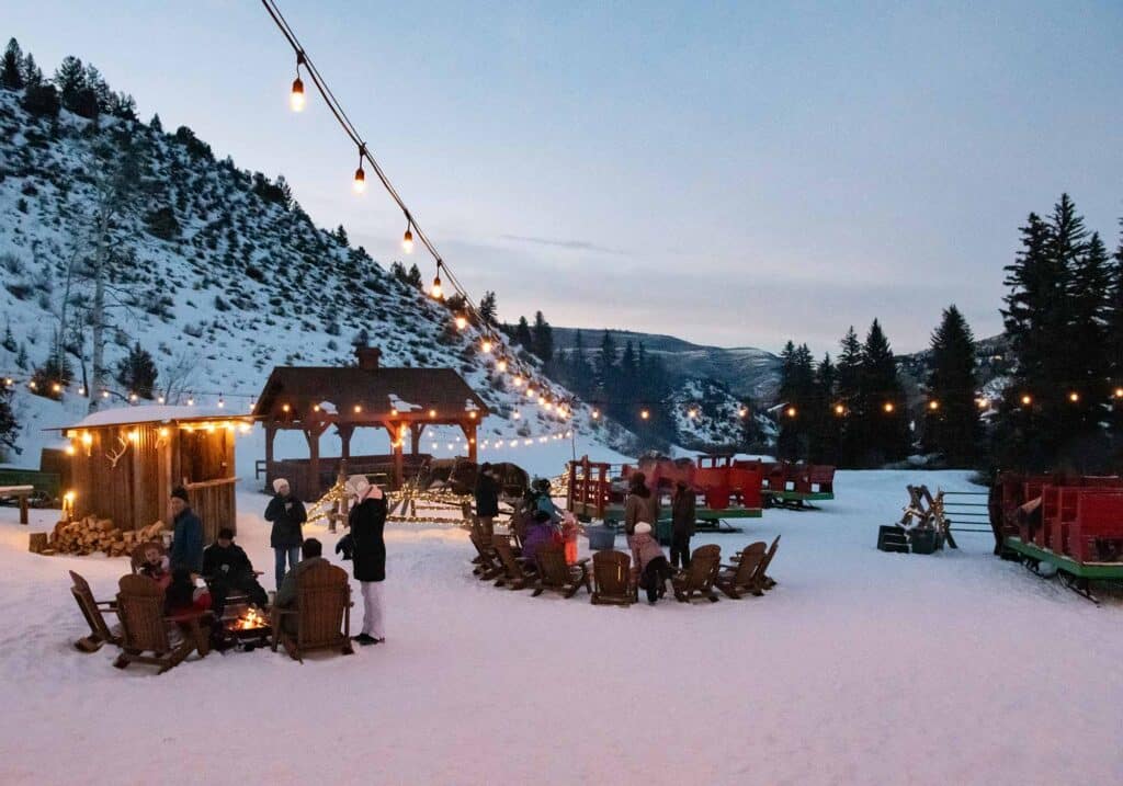Snow-covered patio at Bearcat Stables, surrounded by the Rocky Mountains, offering a cozy winter outdoor seating experience.