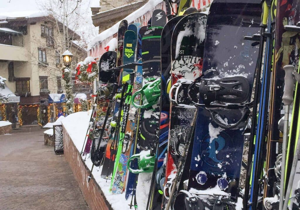 Colorful snowboards propped up in the snow outside shops on a Vail street during winter.