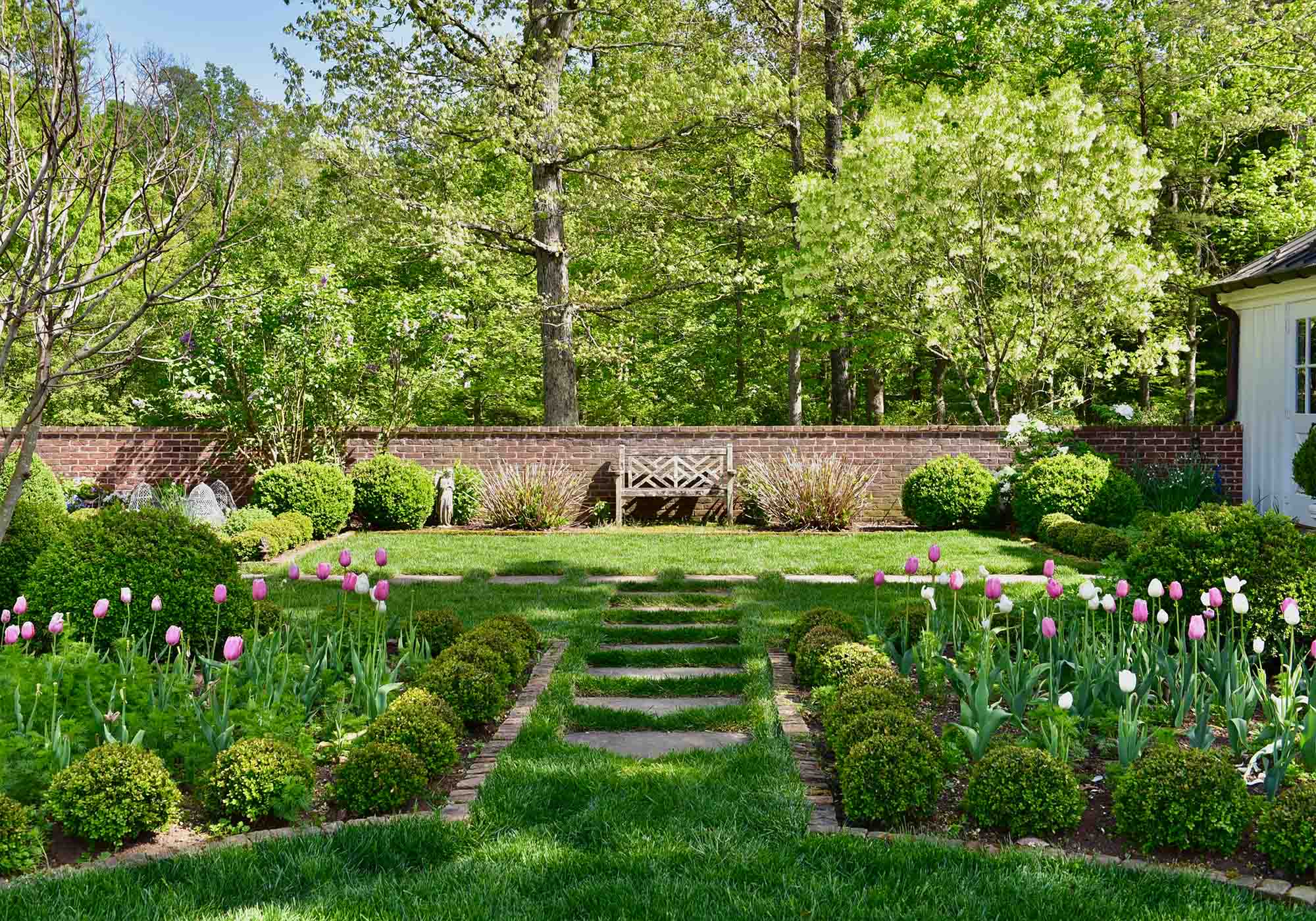 Albemarle County garden with manicured shrubs, blooming tulips, and a wooden bench showcased during Virginia’s 2026 Historic Garden Week