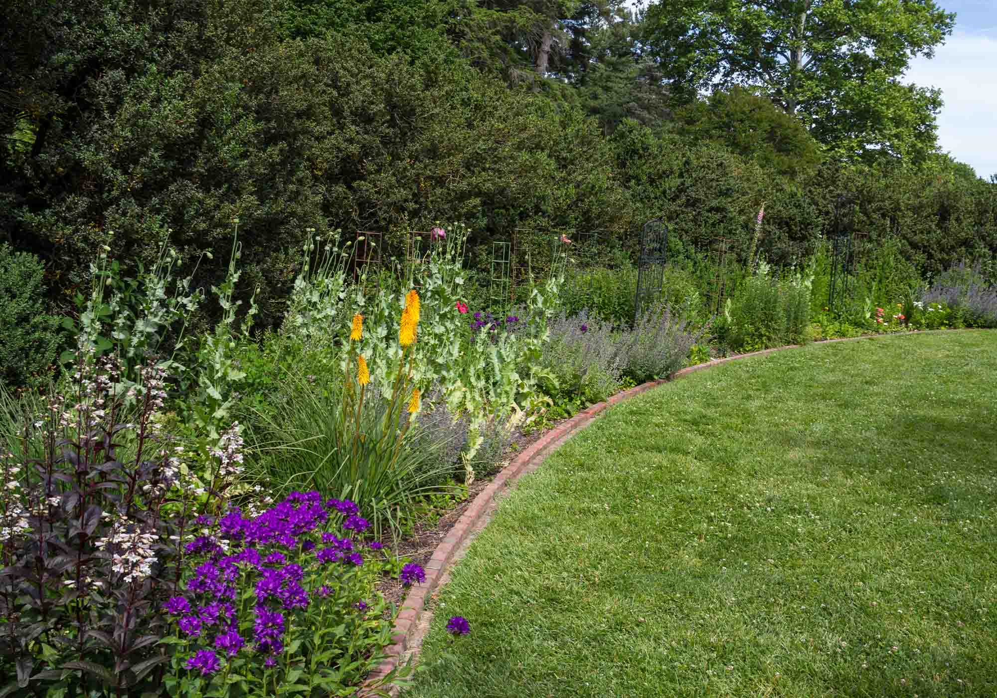 Green Spring Gardens in Alexandria, Virginia with seasonal flowers behind a brick retaining wall during Historic Garden Week 2026