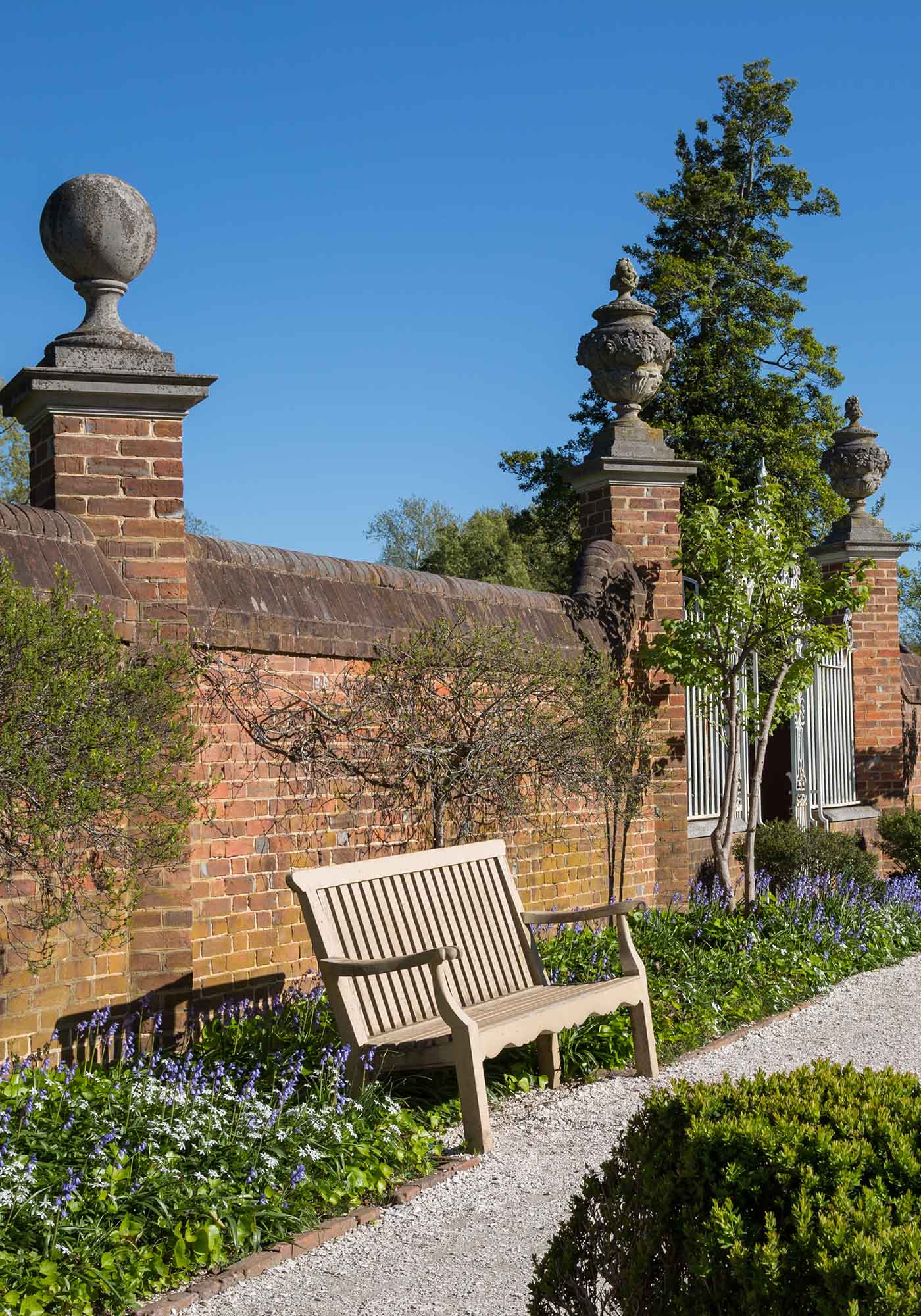 Colonial Williamsburg brick wall and wrought iron gate with bench, showcased during Virginia’s 2026 Historic Garden Week