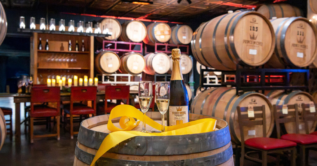 Elegant display of Prince Michel Blanc de Blancs sparkling wine with two glasses on a barrel inside the winery’s new Barrel Cave Tasting Room