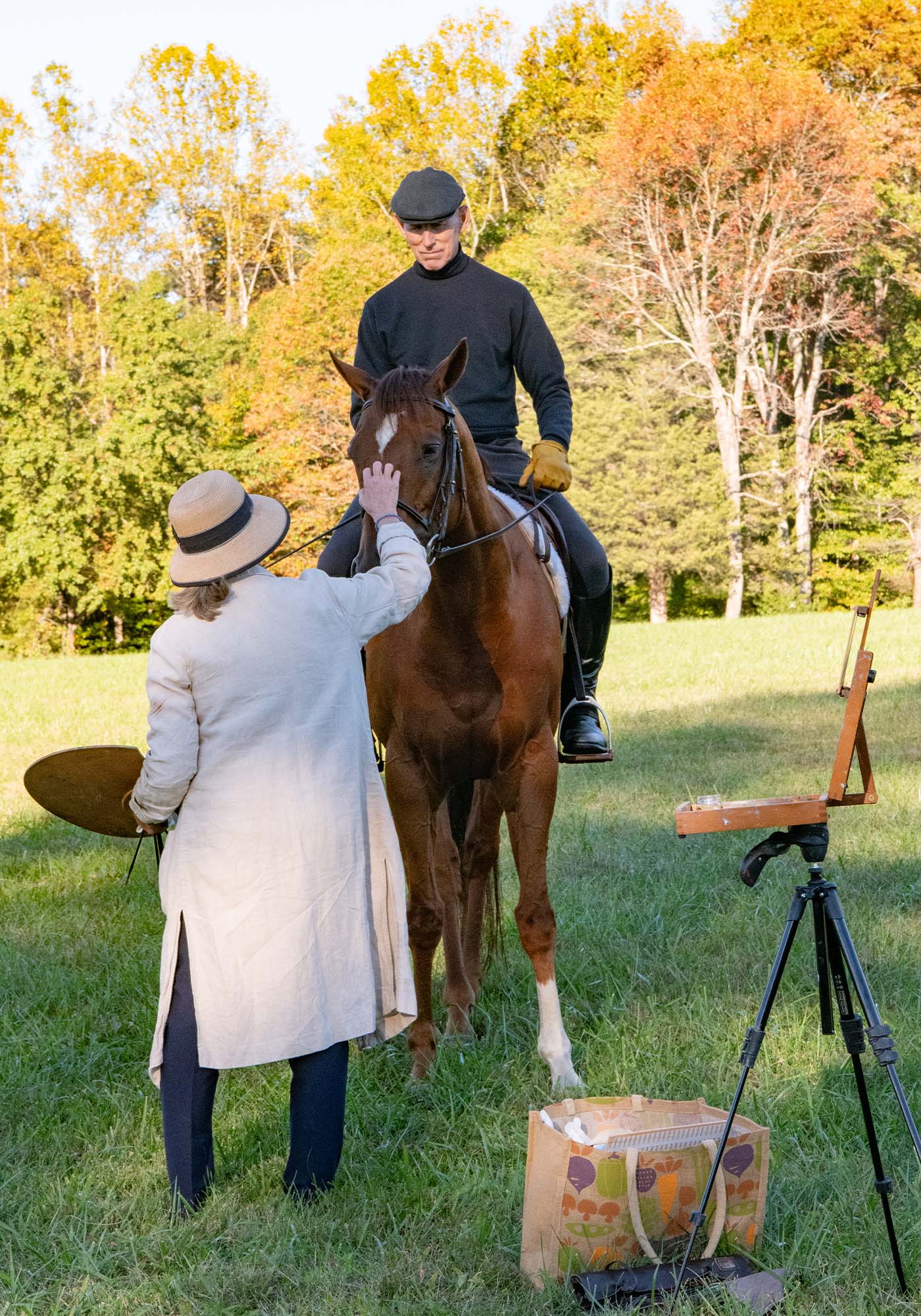 Artist Kelly Wilkinson Coffin greets a horse while holding her painting palette